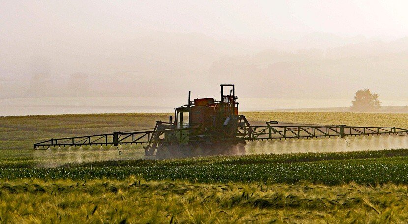 Tractor aplicando pesticidas en un terreno de cultivo.