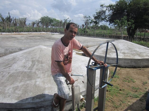 Abel Manto junto a sus cisternas que recogen agua de lluvia mediante una bomba manual que inventó para irrigar sus huertos. El uso de tecnologías como esta para captar y conservar ese recurso le permitieron desarrollar su finca, en el estado de Bahi…
