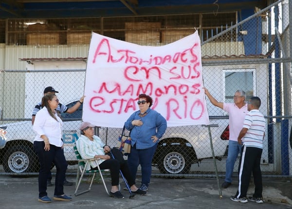 Un grupo de vecinos llevó sillas, pancartas y fotografías, para manifestarse en las afuera de las instalaciones de Grupo Trigal, mientras funcionarios públicos realizaban una inspección. Foto: Albert Marín